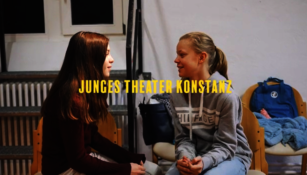 Bild aus der Filmdokumentation des Weiterkommen-Projekts des Jungen Theaters Konstanz. Zwei Mädchen unterhalten sich, überlagert vom Schriftzug "Junges Theater Konstanz".